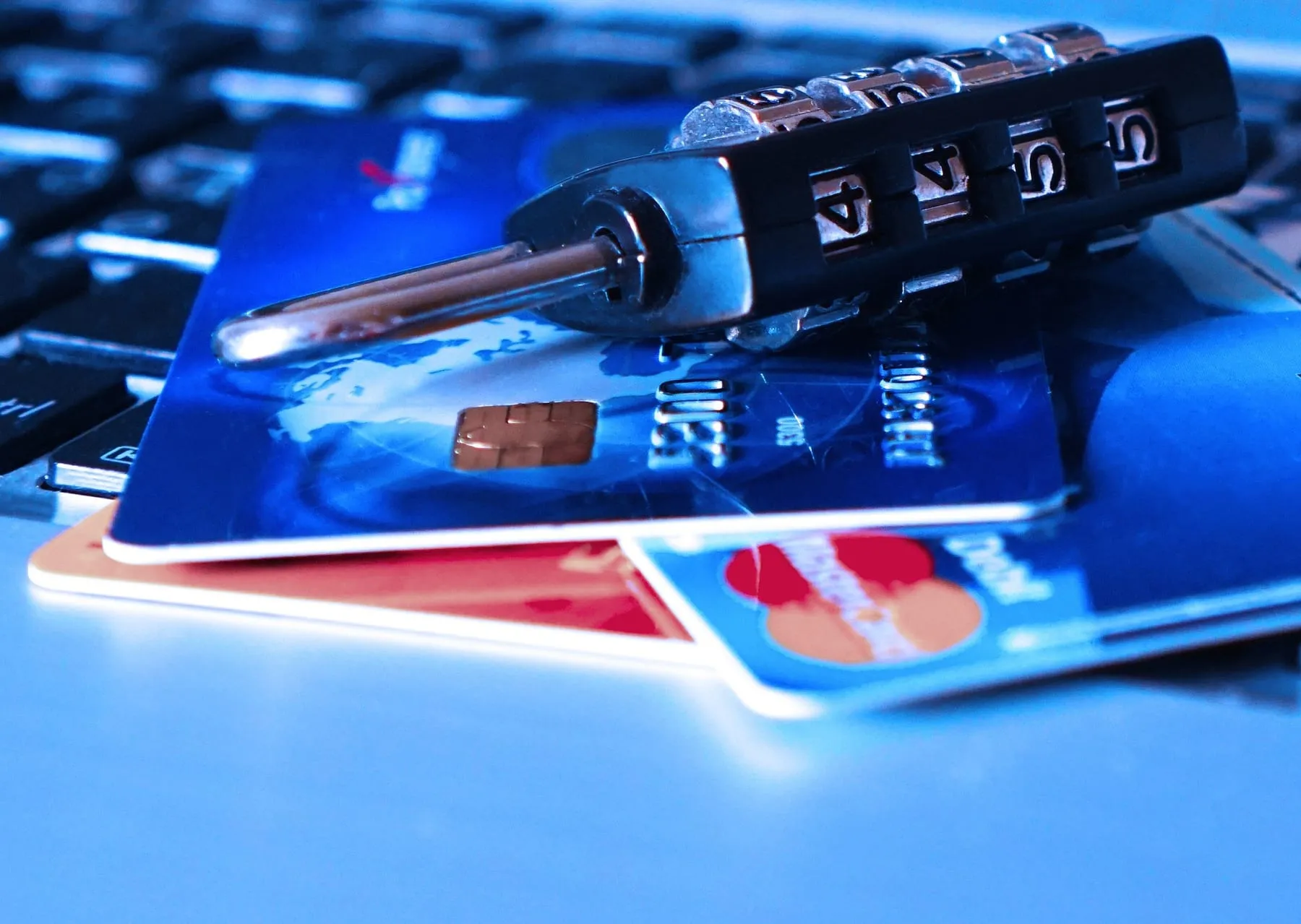 Bank cards on a laptop keyboard under a combination padlock