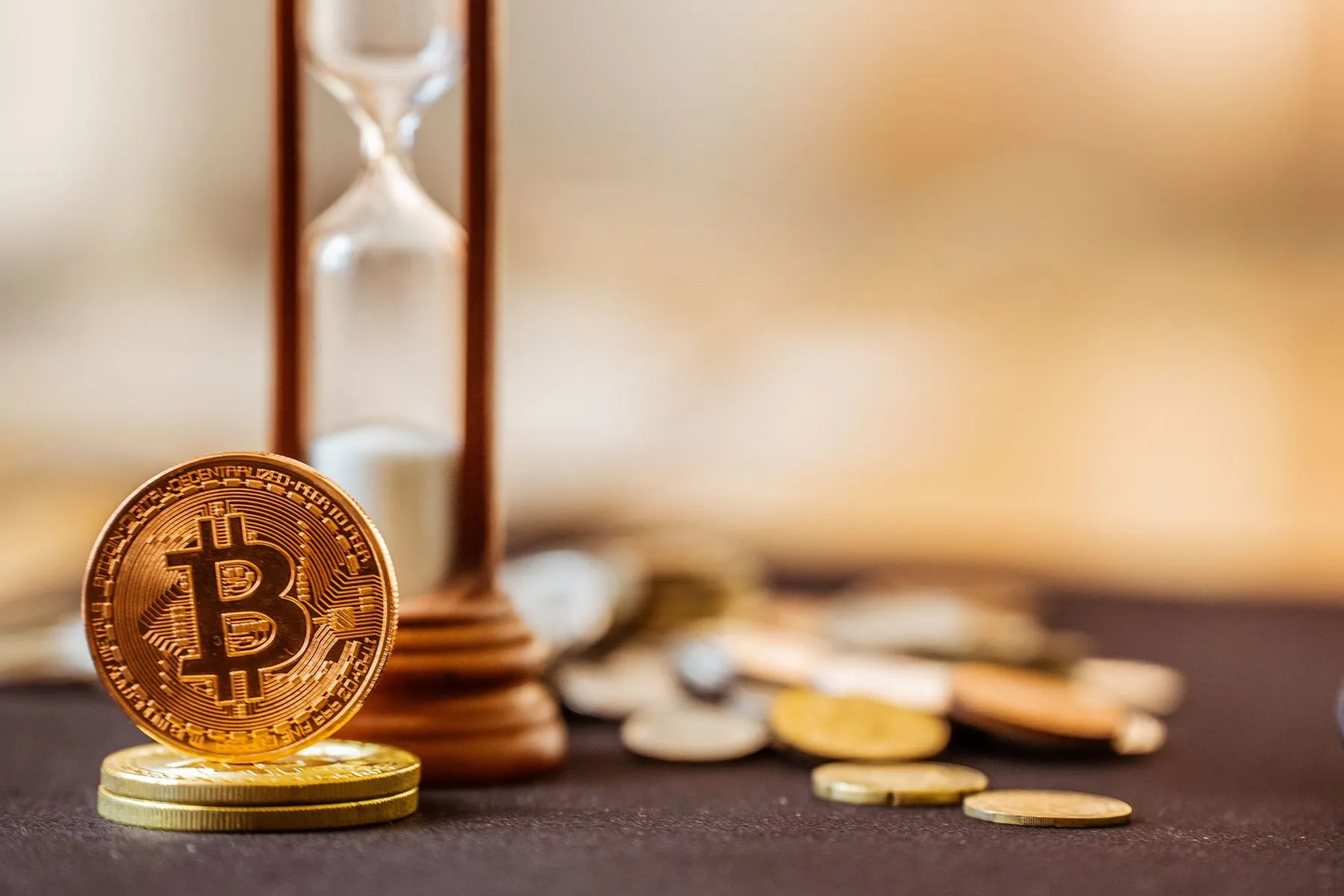 A bitcoin token standing in front of an hourglass
